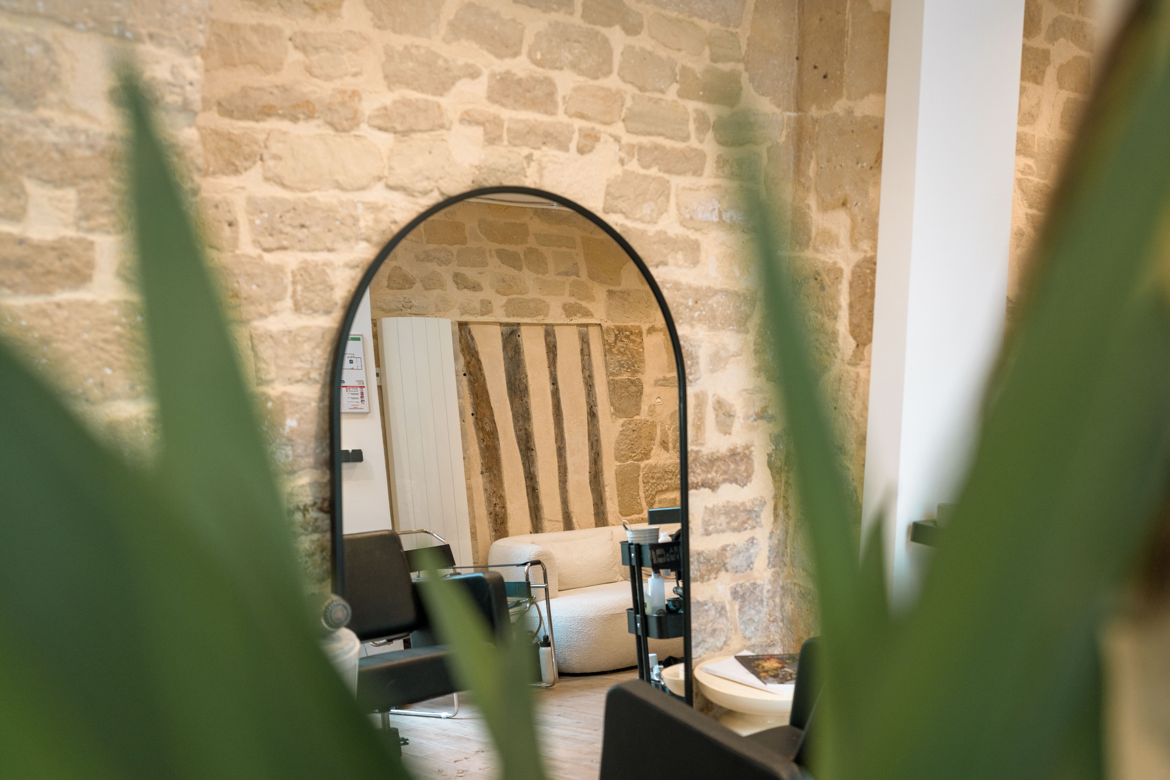 Arc Hair Studio interior — arched mirror against exposed stone wall, Paris 3ème